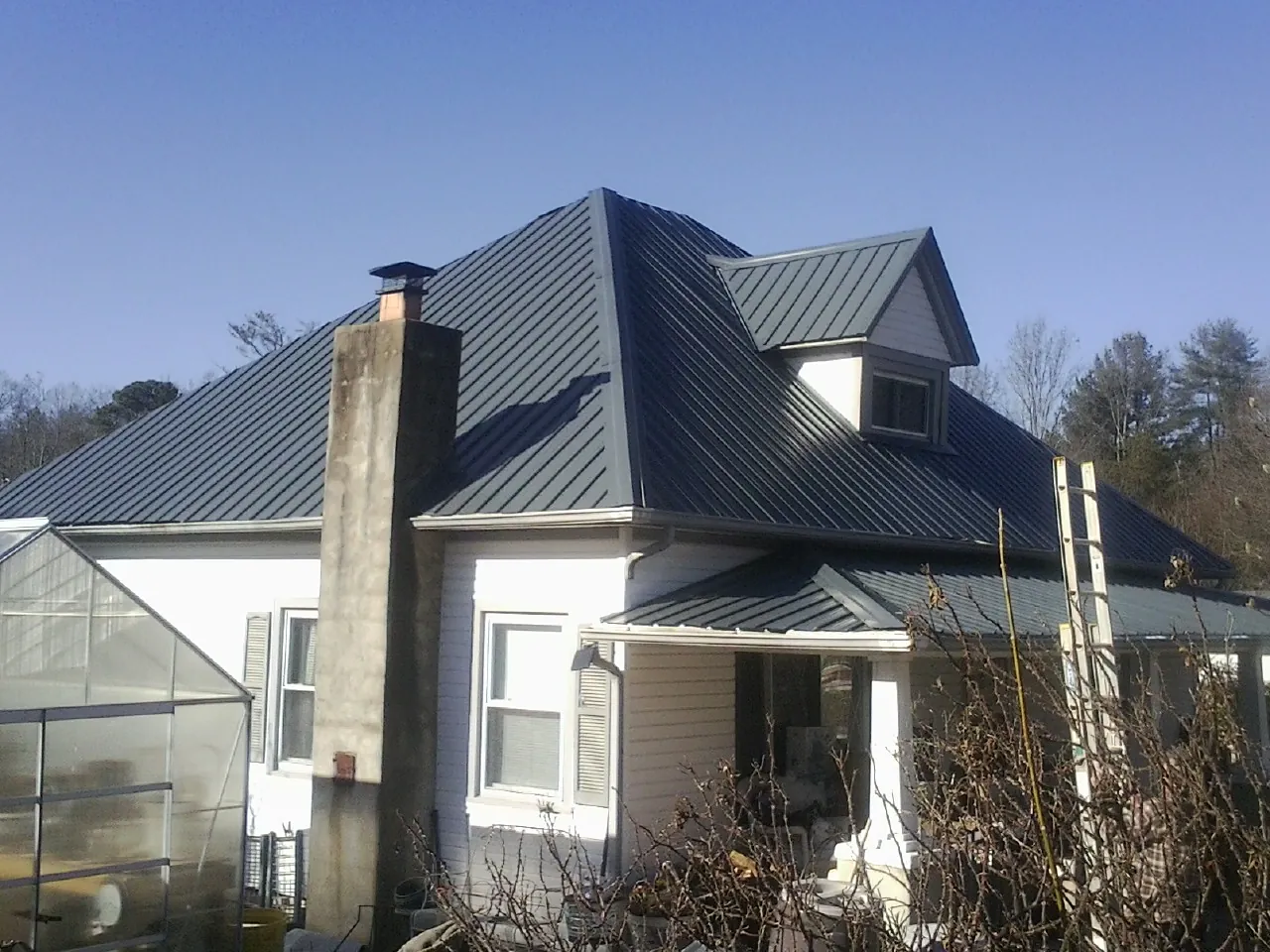 Dark blue standing seam metal roof on a white farmhouse with dormer in Andover