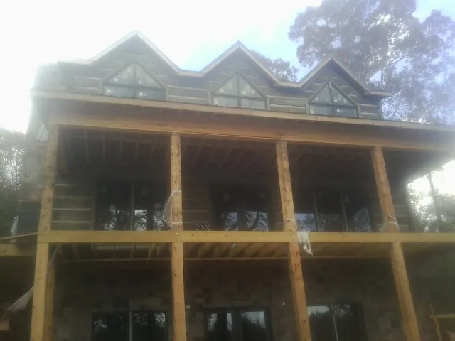 Dormers and porch framing on a large log home under construction — Roof Coating work by our crew in Andover